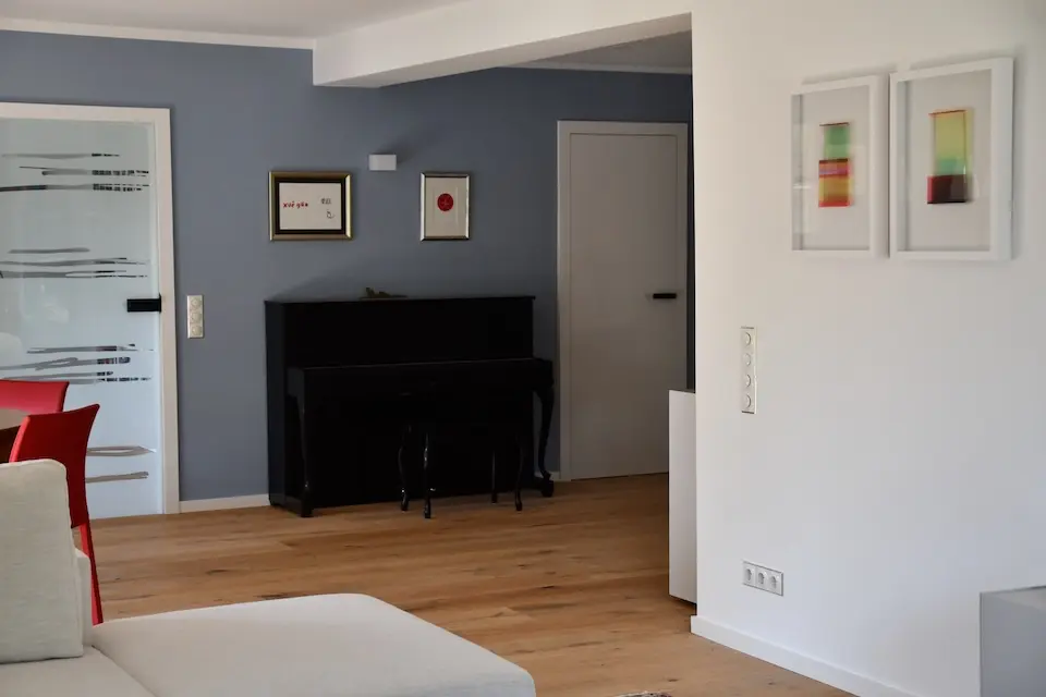 Wohnbereich mit Klavier und blauer Wand – stilvolle Wohnraum-Sanierung mit Farbakzenten