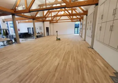 Renovierter Parkettboden im Pfarrheim Korschenbroich mit Holzdecke und Säulen.